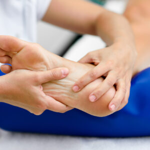 Medical massage at the foot in a physiotherapy center. Female physiotherapist inspecting her patient.